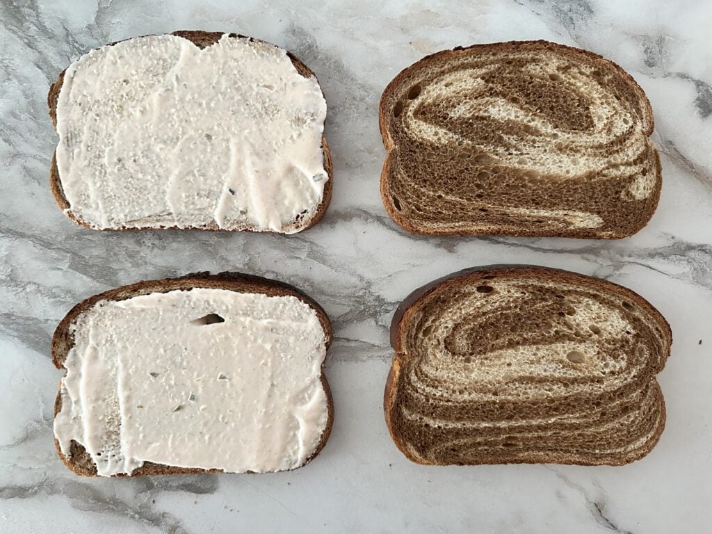 Four pieces of rye bread with two that have Thousand island dressing on them.