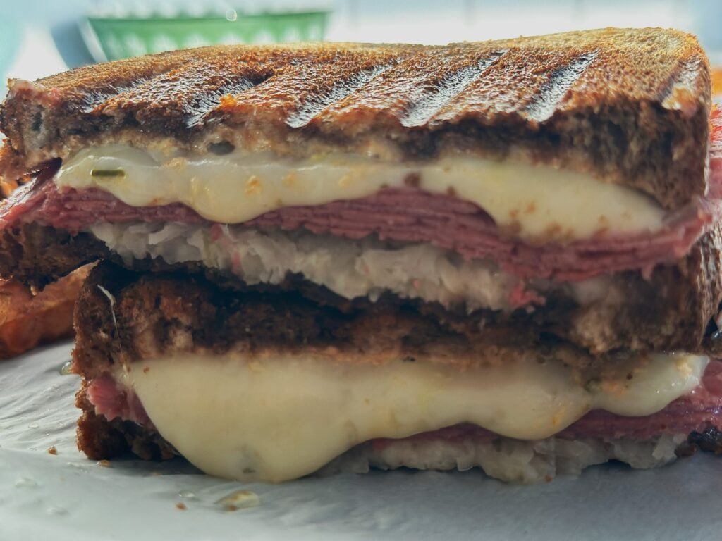 Grilled Reuben sandwich cut in half with the cheese melting.