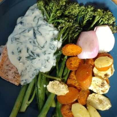 Cooked salmon with broccolini, shallots, sliced carrots and parsnips with a garlic cream sauce with watercress.
