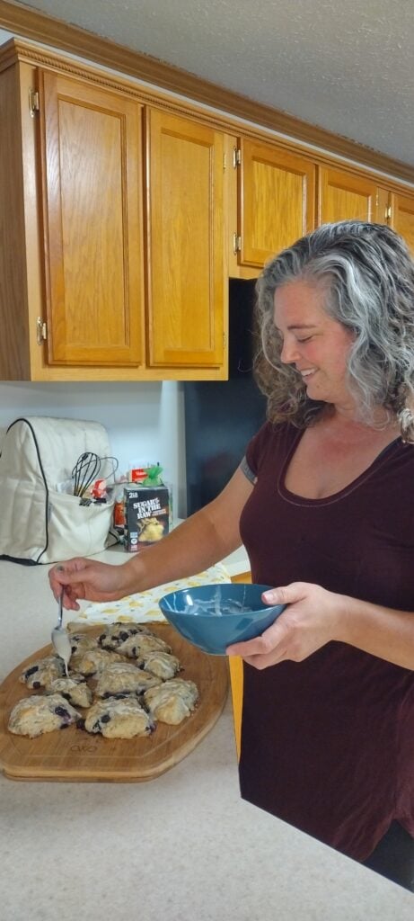 Author drizzling glaze over scones