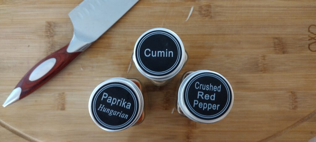 Cumin, paprika, crushed red pepper in jars.