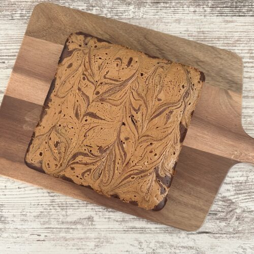 8x8 square peanut butter brownie on a wooden cutting board.