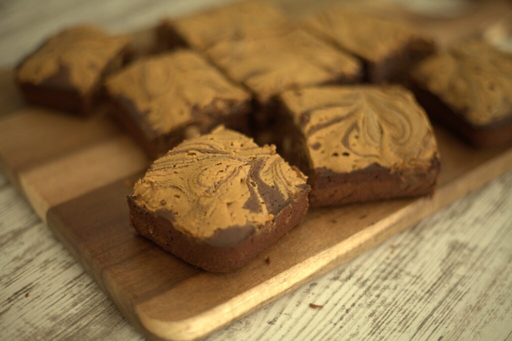 Eight slices of peanut butter brownies arranged on wooden cutting board.