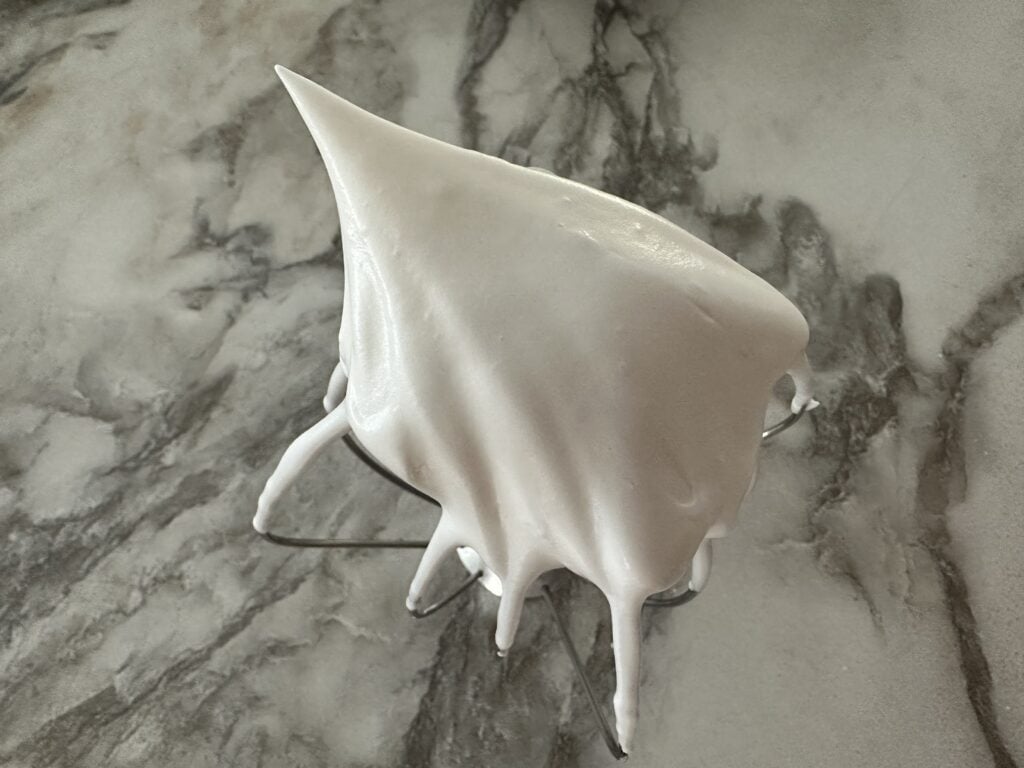 Whipped meringue on a whisk.