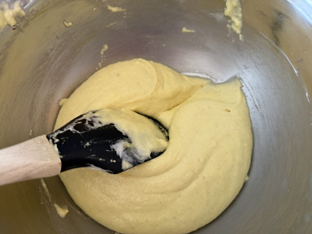 Dragging a spatula through the macaronage to deflate air, making a cohesive batter.