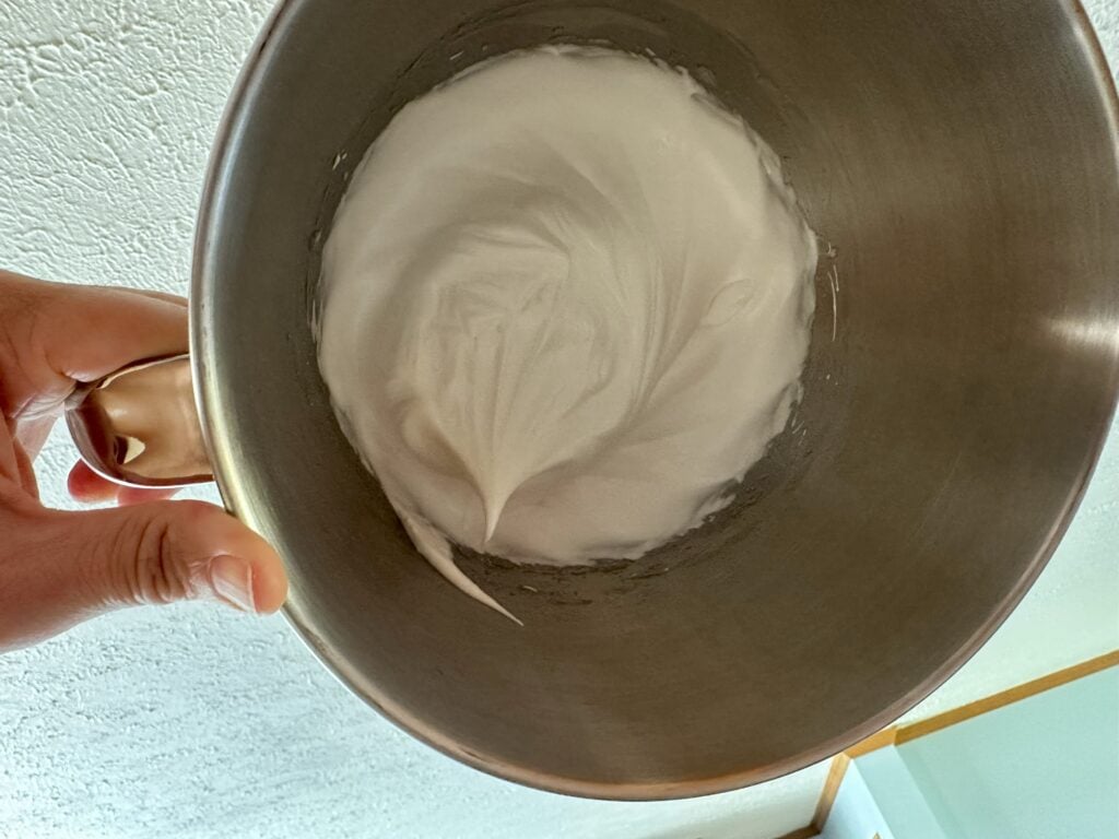 Meringue in a bowl that is upside down showing the stiff peaks indicating a properly whipped meringue.