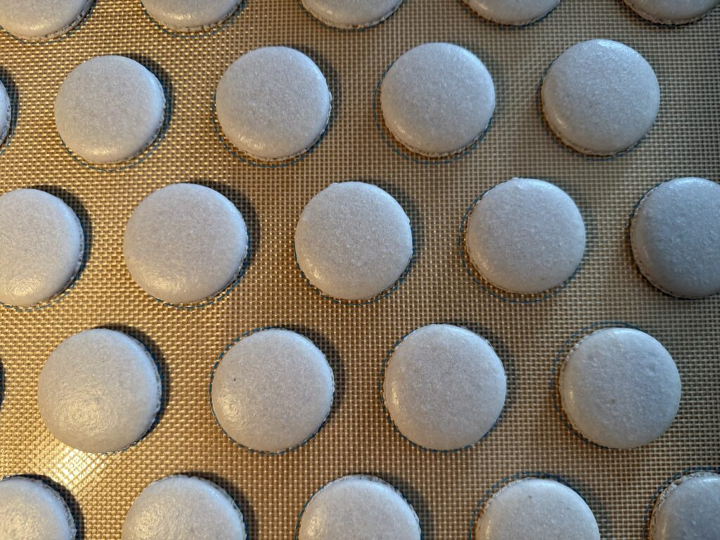 Baked macarons shells on silicone mat.