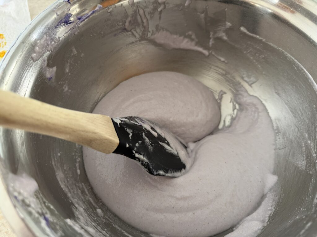 Dragging spatula through macaronage to help deflate it and form a cohesive batter.