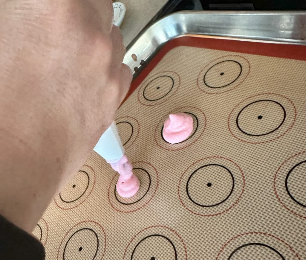 Piping the batter onto a silicone lined baking sheet.