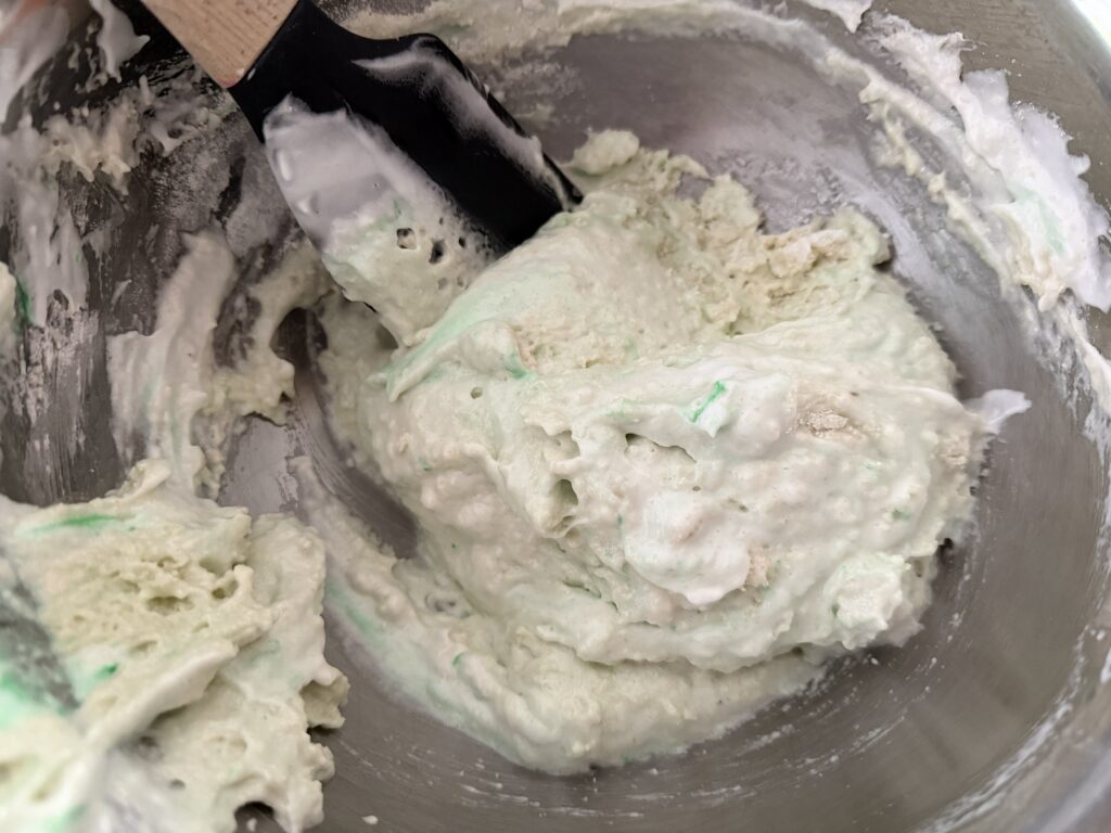 Meringue being mixed with almond flour and powdered sugar.