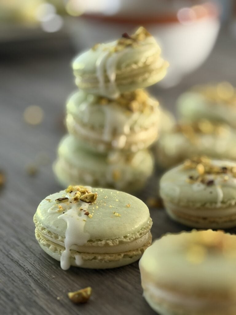 Pistachio macarons arranged on a surface with three stacked on top of each other.