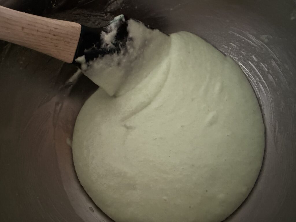 Demonstrating the technique of scraping the bowl to make a cohesive batter.