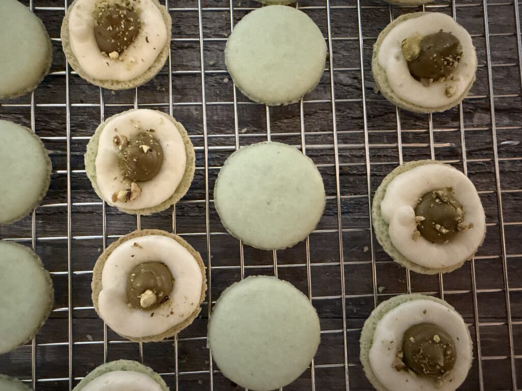 Open faced pistachio macarons showing the filling.