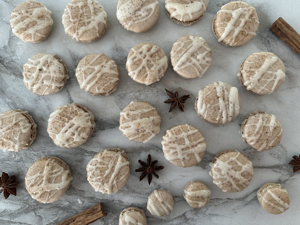 Chai macarons arranged on a surface with star anise.