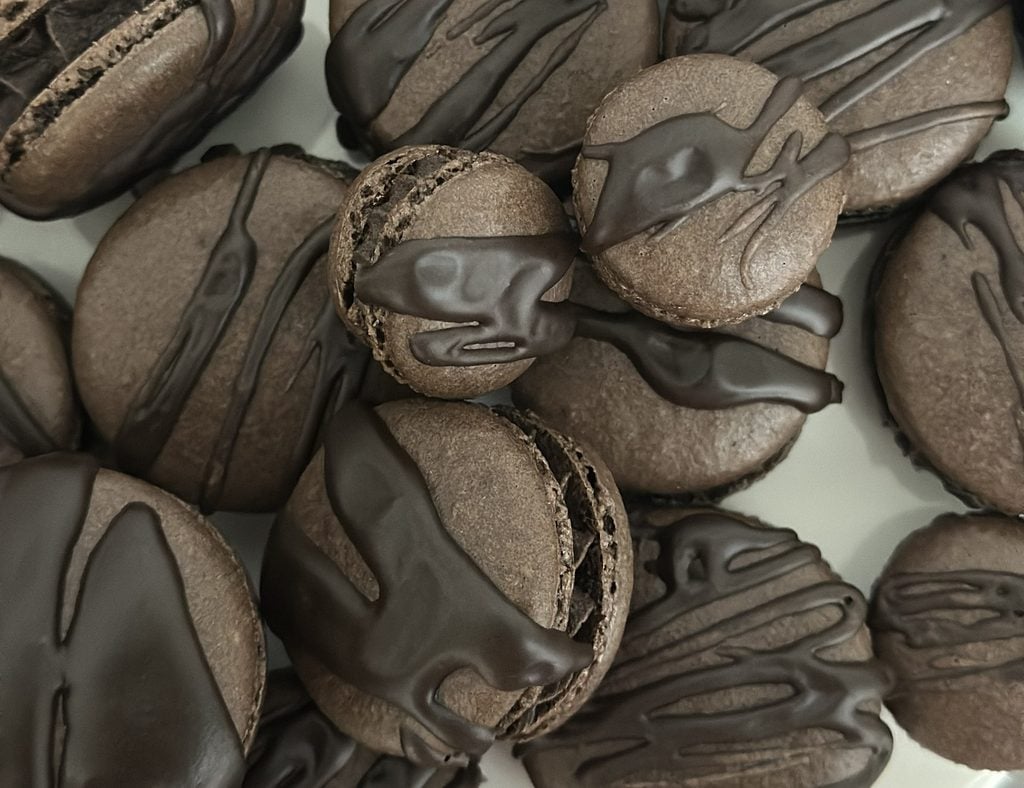 Dark chocolate espresso macarons stacked on a surface.