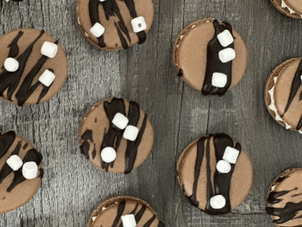 Hot chocolate macarons arranged on a surface.